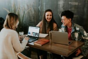 three people sitting in front of table laughing together. adhd access to work. ADHD Therapy