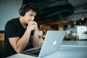 man wearing headphones while sitting on chair in front of MacBook - adhd coaching online